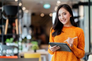 Como abrir uma microempresa - imagem de empresária sorrindo com tablet na mão ao abrir um CNPJ ME